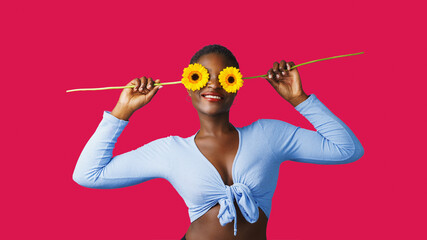  Portrait of a happy young woman holding orange Gerbera daisy covering her eye with eyes closed