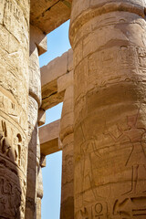 Tall columns of historical complex of Karnak temple with carved ancient Egyptian hieroglyphs and symbols. Great Hypostyle Hall at Temples of Karnak (ancient Thebes). Luxor, Egypt. Selective focus.