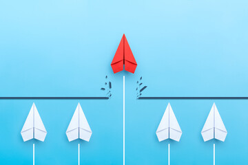Red paper plane breaking through obstacle on blue background, Concept of overcoming barriers, goal,...