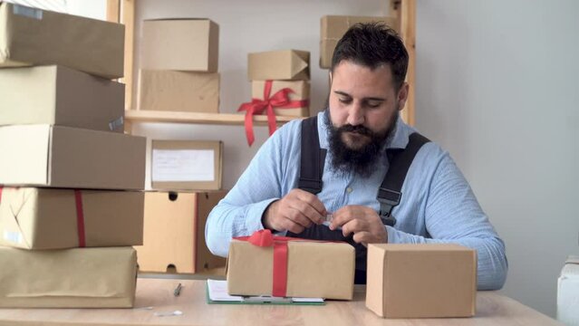 hindu male business owner working from home in uniform with packing box at workplace - online buying or selling online concept. sticks a barcode on a craft box