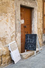 Charming handwritten sings in a street of Valetta, Malta placed in front of a brown wooden door...
