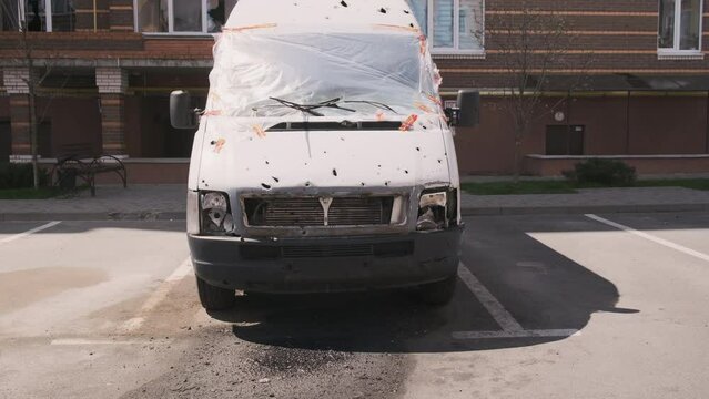 Irpin, a shot car, a cargo minibus, in the parking lot near the house. War in Ukraine, consequences of shelling