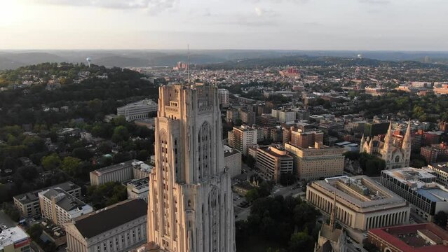 A cinematic orbiting aerial establishing shot of the Cathedral of Learning. Shot revolves to reveal the Pittsburgh skyline in the distance.