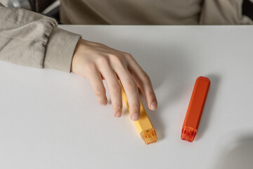 electronic cigarettes in the hands of a teenager sitting at a white table, danger to health and...