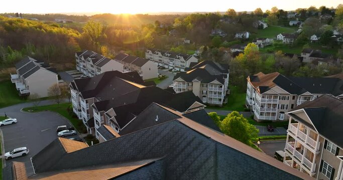 Colorful sunset over residential apartment building units in USA. American living. Aerial establishing shot with bright warm starburst effect.