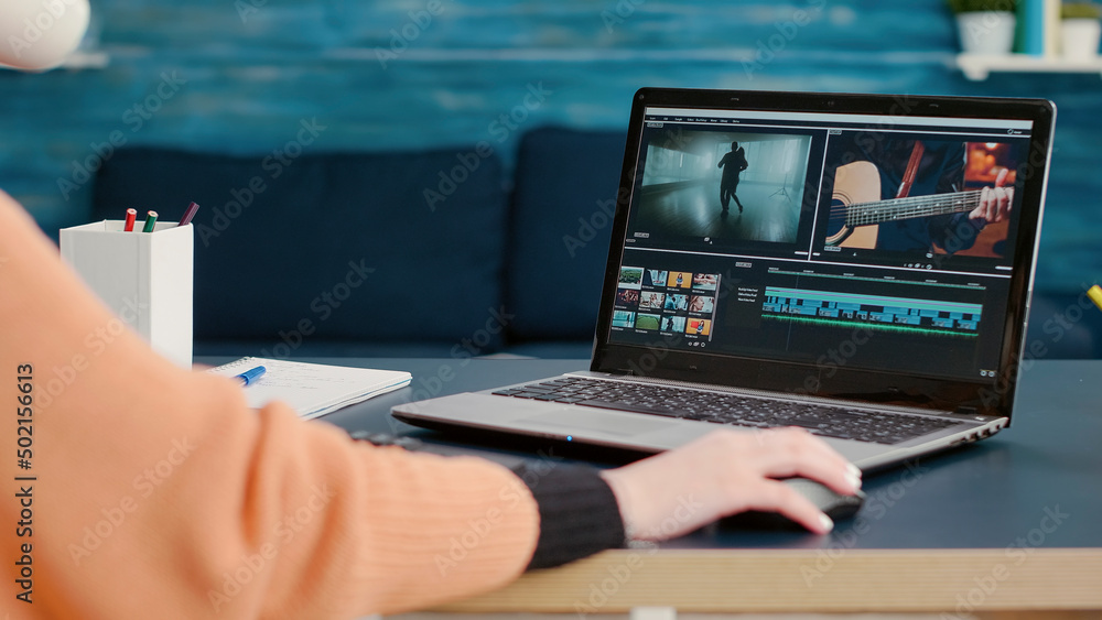 Poster multimedia designer using software to edit video footage on laptop at desk, learning to use producti