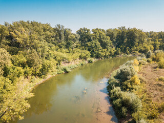 Aerial top view of a peaceful river valley among green plain. Summer scene and eco environment.