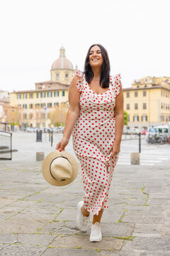 Smiling curvy woman wearing polka dot dress standing in city