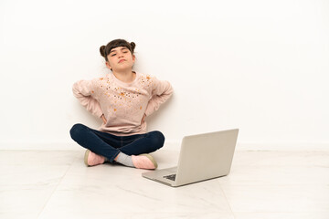 Little girl with a laptop sitting on the floor suffering from backache for having made an effort