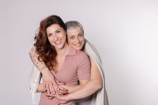 Happy friends with blanket standing against white background