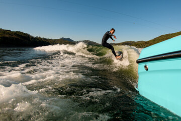 great view on active man on a wakesurf skillfully riding on a splashing wave