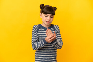 Little caucasian girl isolated on yellow background suffering from pain in hands