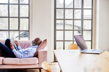 Businessman with headset working on tablet computer in living room