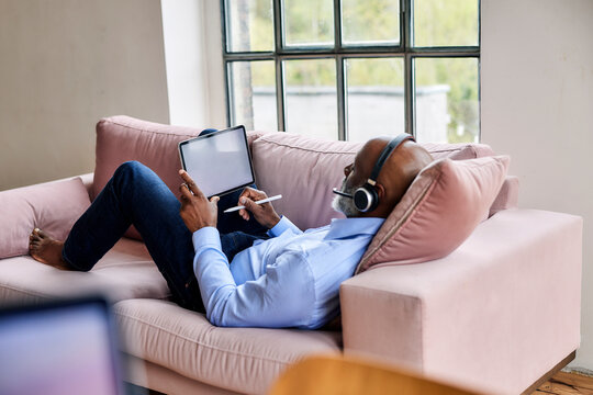 Businessman with headset using tablet PC on sofa at home