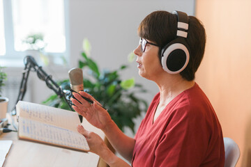 Middle-aged female radio presenter talking into the microphone and reading news - radio broadcast...