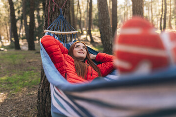 Smiling young woman with hands behind head lying in hammock