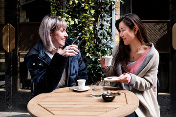 Two multiracial mature women friends having a coffee.