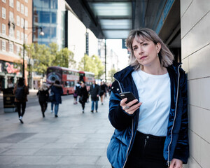 Fototapeta premium Mature woman with a mobile waiting at station door.