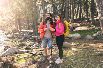 Young woman with smart phone standing by disabled boyfriend in forest