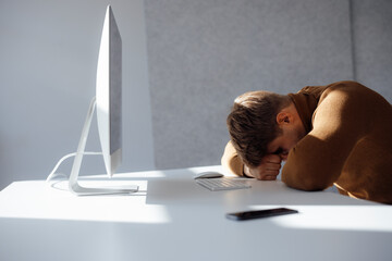 Businessman resting head on desk in office