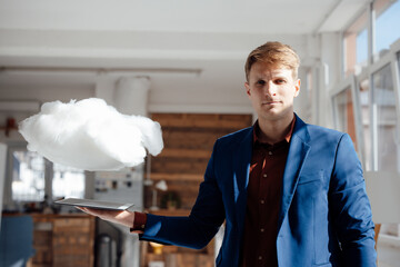 Businessman holding tablet PC under levitating cloud network in office