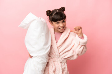 Little caucasian girl isolated on pink background in pajamas and proud of self-satisfied