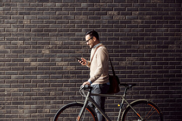 A businessman going to work with bicycle and looking at the phone.