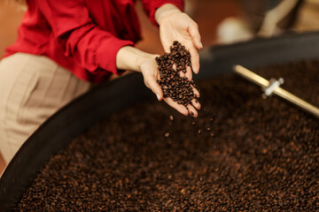 A woman's hands holding coffee beans in coffee factory.