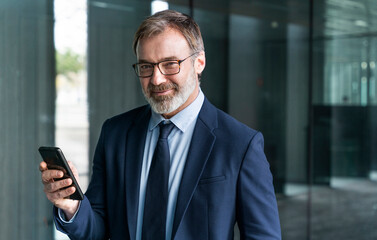 Smiling businessman holding smart phone
