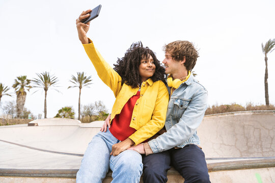 Smiling woman taking selfie with boyfriend on wall