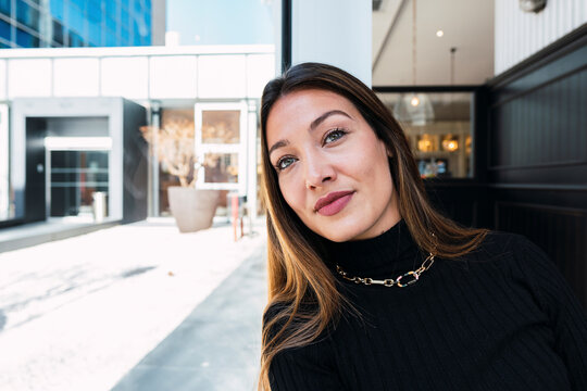 Thoughtful Woman With Long Hair Leaning Head On Glass Wall In Cafe