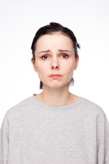 emotional woman in a gray sweatshirt, white background