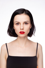 brunette woman with red lips in black top, white studio background
