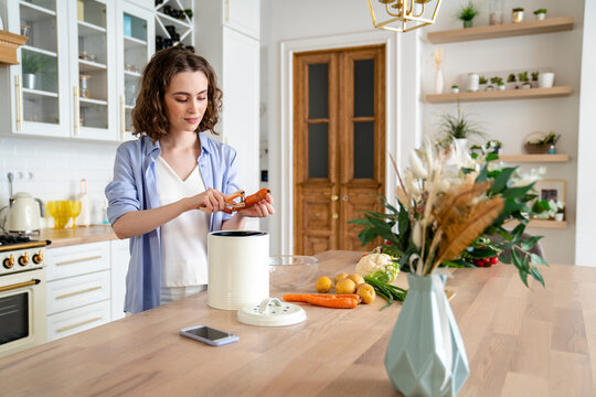 Young woman peeling carrot at dining table in kitchen