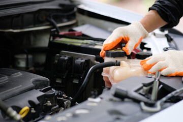 Hands of an automobile mechanic repairman repairing a car engine at an automotive workshop with a wrench, car servicing and maintenance,Repair service