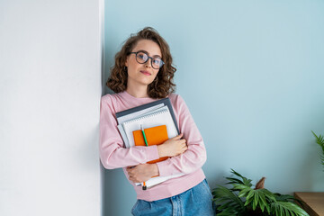 Confident woman with books leaning on wall