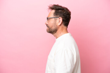 Middle age caucasian man isolated on pink background With glasses