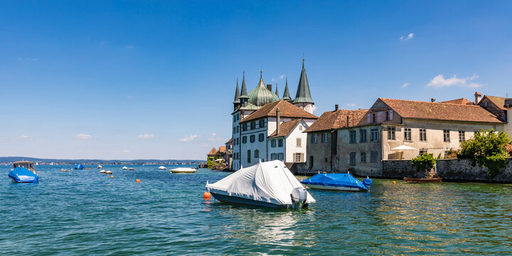Switzerland, Thurgau, Steckborn, Shrink wrapped boats floating near shore of Lake Constance with town houses in background