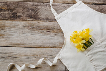 Narcissus flowers bouquet in the apron on a wooden table. Florist concept. top view. 