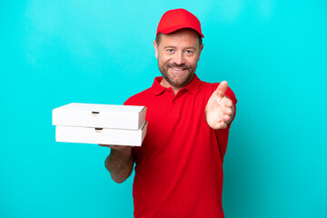 Pizza delivery man with work uniform picking up pizza boxes isolated on blue background shaking hands for closing a good deal