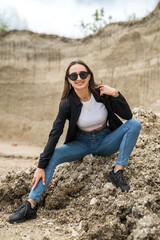 slim sporty girl in a casual clothes posing against the rocks of sand in quarry