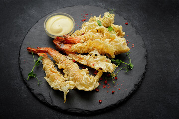Tempura shrimps with sauce, on a dark background