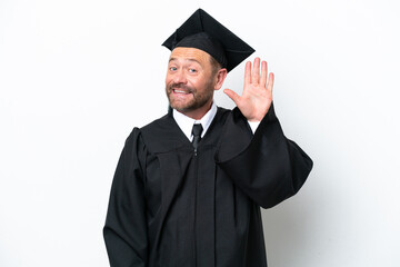 Middle age university graduate man isolated on white background saluting with hand with happy expression