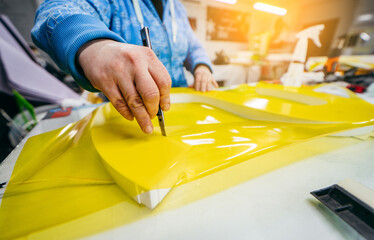 Applying colored yellow membrane to a surface of plastic 3d letter of signboard. worker's hands...