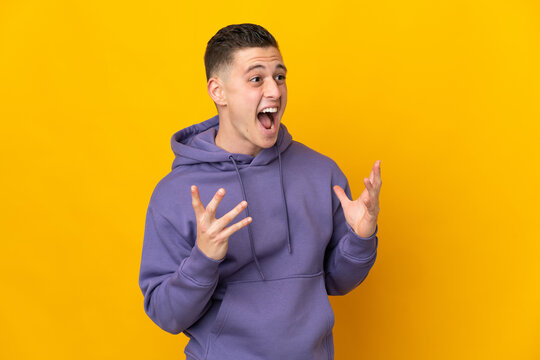 Young caucasian man isolated on yellow background with surprise facial expression