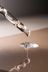 Pipette with serum, gel, oil or other cosmetic product on a beige background.