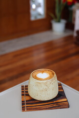 Coffee cup with latte art on the wood table.