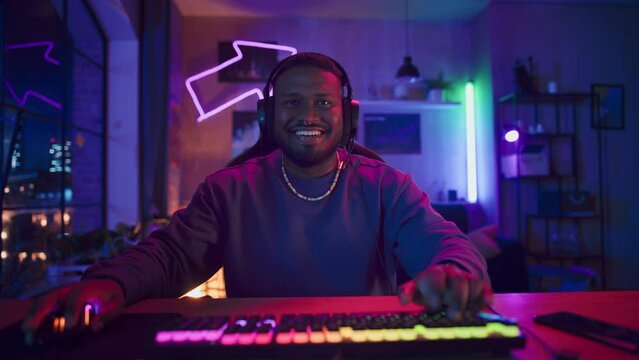 Gaming at Home: African American Gamer Putting on Headphones and Playing Online Video Game on Computer. Successful Black Man Winning in Online Multiplayer Tournament. POV from Screen Perspective.