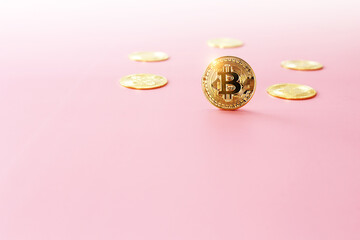 Close up golden bitcoin coin on light pink background. Cryptocurrency symbol. The shiny bitcoin gold coin stands out in front of other coins with copy space.