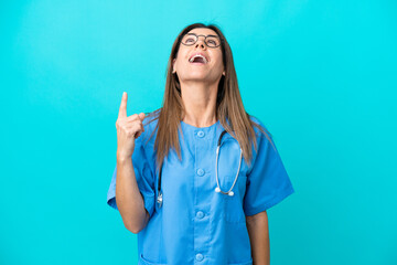 Middle age surgeon woman isolated on blue background pointing up and surprised